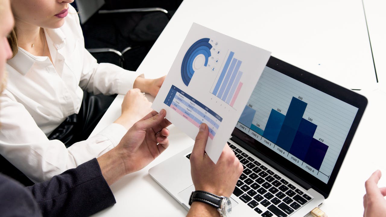 our-services-2 Business professionals discussing data charts and graphs in a modern office setting.