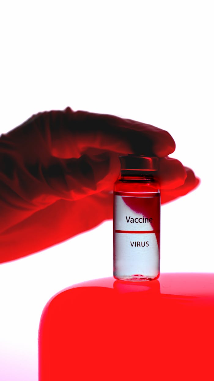 our-services-1 A close-up of a vaccine vial held by a gloved hand under red lighting, conveying medical research.