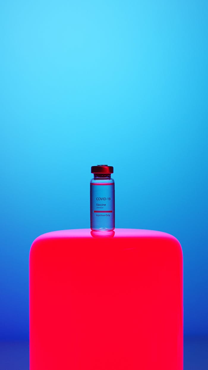 about-01 COVID-19 vaccine vial on a vibrant neon pink background against a blue gradient backdrop, symbolizing modern healthcare.